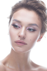Fototapeta premium Young girl with a gentle nude makeup and hairstyle. Beautiful model with shining perfect skin. Beauty of the face. White isolated background.