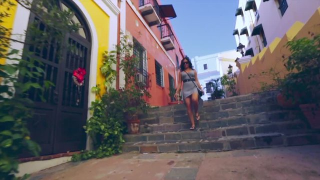 Slow motion of woman walking down stairs in colorful street in Old San Juan