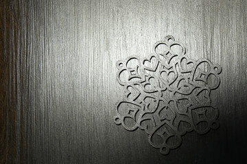 Silver snowflake ornament on silver background. Laser cut christmas decoration wood snowflake on...