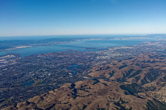 Aerial view of South San Francisco Bay foothills, San Francisco Bay, Coastal mountains, Pacific Ocean, and blue sky.