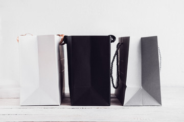 Three stylish paper shopping bags in white, black and gray colors against white background. Copy space for text