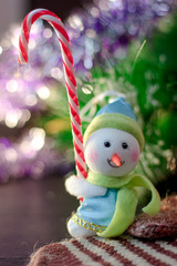 Toy snowman holding christmas candy cane in hands.