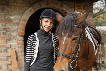  Teenage girl with her horse in front of a stable