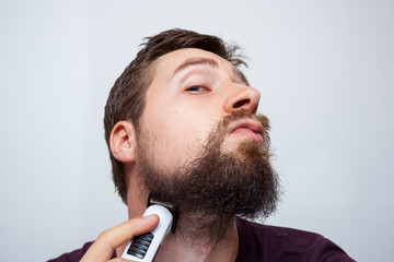 Young bearded man trimming his unkempt beard