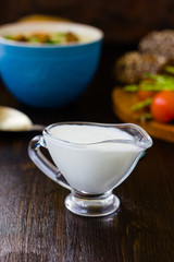 Natural cream dip in a glass bowl on dark wooden board.