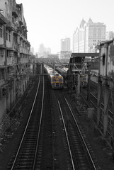 Naklejka premium Suburban Railway. The train approaches the station against the background of tall buildings