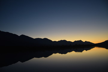 Last glimpse of a sunset with mountain silhouette in the water