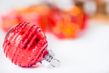 Close-up of red xmas ball with blurred colorful Christmas decor in background. Christmas and New Year concept with copy space. Christmas greeting card.