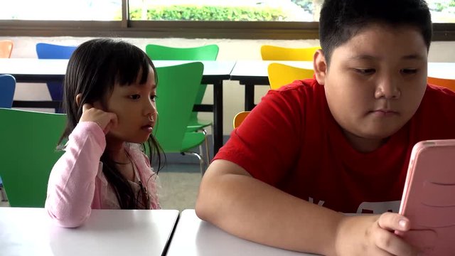 Asian child Boy and girls are addictive playing tablet and mobile phones, Game Addiction