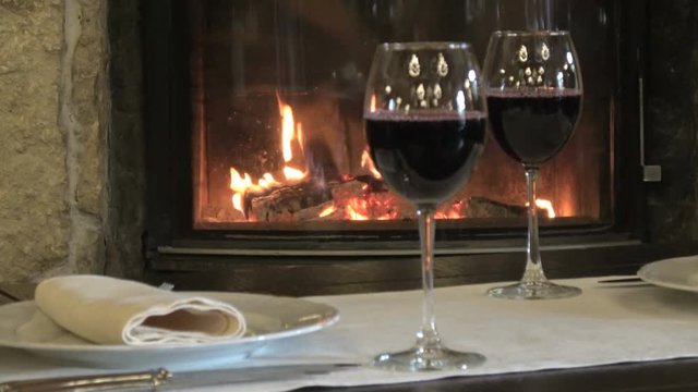 Two glasses of red wine on the background of a burning fire in the fireplace