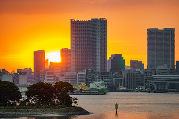 Sunset over office buildings in Tokyo with water reflection