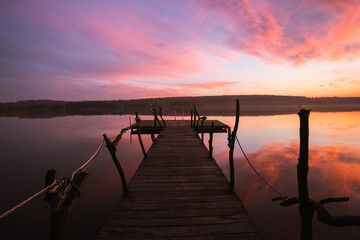 Obraz premium Perspective view of a wooden pier on a river at sunset