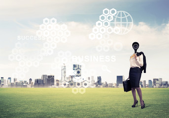 Camera headed woman standing on green grass against modern citys