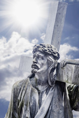 Fototapeta premium The road to Golgotha. Ancient statue of Jesus Christ with cross. (holy, faith, religion, God, suffering concept)
