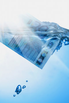 Money concept showing Euro banknote sinking in water as a symbol of global economic crisis