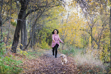 Fototapeta premium Asian girl walking with her dog in the park. A girl runs after a dog