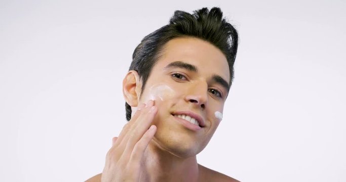 Close up of a man with moisturizer for his face smiling because he hydrates his skin and protects against impurities with anti-aging effects. Concept of: beauty and body care, creams, skincare