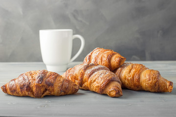 Four croissant sprinkled with powdered sugar on a gray background
