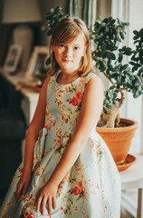 Interior portrait of pretty little girl wearing blue dress