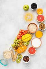 Healthy breakfast with oats, variety of fruits, strawberries, mango, grapes, figs, yogurt and nuts served on the white table, top view, copy space for text, selective focus