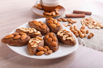 Small cakes "potatoes" with almonds and cashew nuts.  A cup of coffee, cinnamon, almonds, hazelnuts, cashew on a linen napkin.