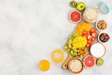 Healthy breakfast with oats, variety of fruits, strawberries, mango, grapes, figs, yogurt and nuts served on the white table, top view, copy space for text, selective focus