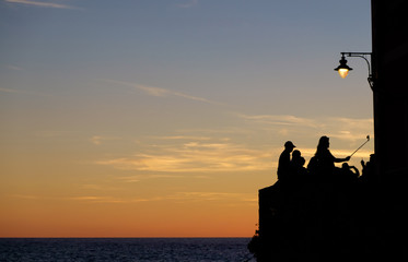 Silhouettes of people taking selfies at sunset in Cinque Terre, Italy