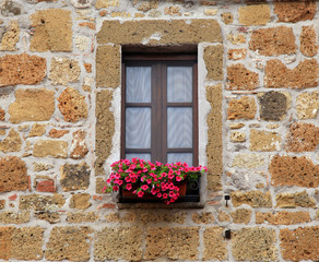 Fototapeta na wymiar italian window with nice flowers in old stone house, Tuscany, Italy.