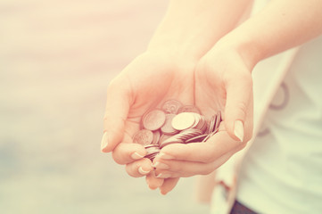 Handful of coins in palm female hands. Concept of saving and passive income. Red instagram toned