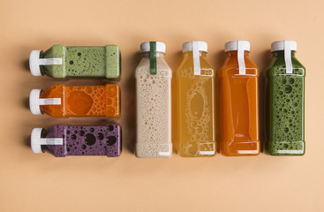 Healthy detox juice in plastic bottles on soft orange background. Colorful bottles. Healthy organic...