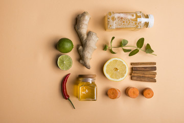 Organic detox juice with ginger, mint, lemon and lime ingredients on soft orange background. Tabl top view. Flat lay. Healthy frsh products