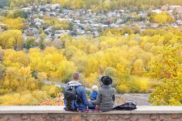 Parents and son looking at the city from a height. Autumn. Back view