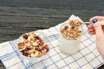 Female hand pours in yogurt granola. Traditional American Breakfast