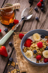 breakfast cereal close-up shot on wood boards top view with raspberries blueberries bananas strawberries and a  spoon portrait