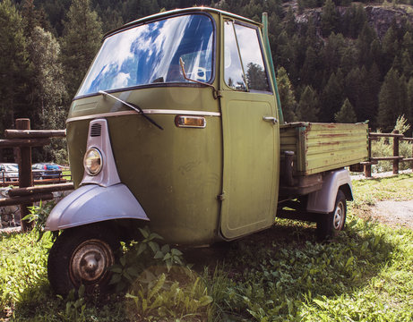 Ape car green framed from below in natural landscape