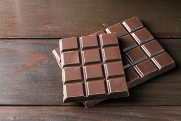 Bitter, dark chocolate bar on wooden planks background