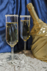 Wine glasses with champagne on a background of Christmas candles and balls and a Christmas tree.