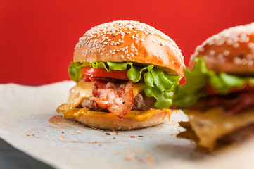 delicious homemade burgers with a juicy veal cutlet on a wooden table, against a red wall background