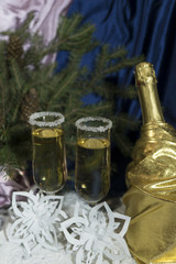 Wine glasses with champagne on a background of Christmas candles and balls and a Christmas tree.