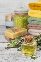 Natural cosmetic oil and natural handmade soap with rosemary on rustic wooden background.