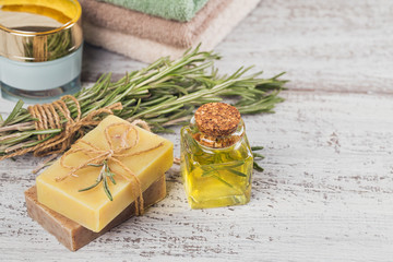 Natural cosmetic oil and natural handmade soap with rosemary on rustic wooden background.