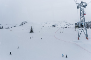 Skiers and snowboarders going down wide open slopes of Whistler Blackcomb from above