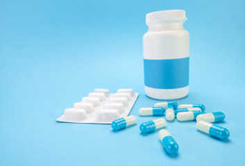 Pills spilling from an open bottle isolated on blue  background