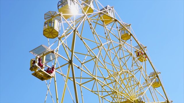 Close up shot of a big yellow wheel turning on fair during daylight. sun is shining and wheel reflects the light.