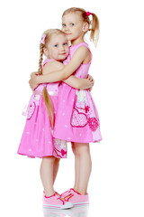 Two little girls hug.