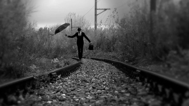 man with umbrella walking on railroad,black and white color