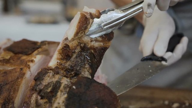 The chef slicers the juicy meat of the baked pig