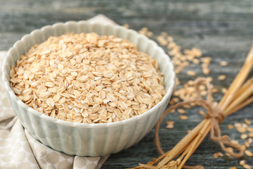 Bowl with oatmeal flakes on wooden background