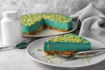 Plate with piece of tasty spirulina cheesecake on table