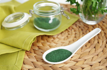 Composition with spirulina powder in spoon on wicker mat